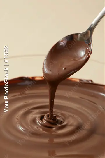 Silver Spoon Pouring Melted Dark Chocolate into Bowl