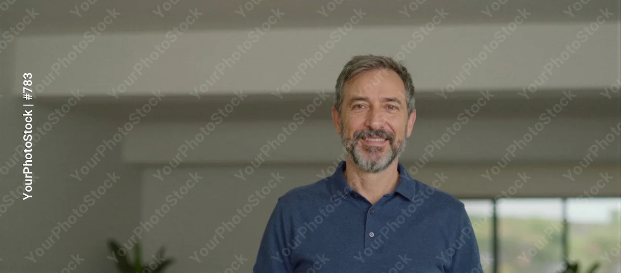 Middle-aged man with beard and mustache smiling in an empty room