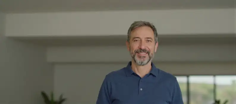 Middle-aged man with beard and mustache smiling in an empty room
