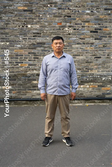 Middle-aged man in front of brick wall looking serious asian