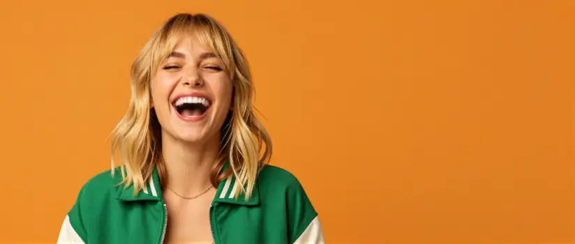 Young Woman Laughing with Closed Eyes, Green Jacket, Blonde Hair