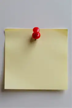 Blank Yellow Sticky Note with Red Pin on White Wall