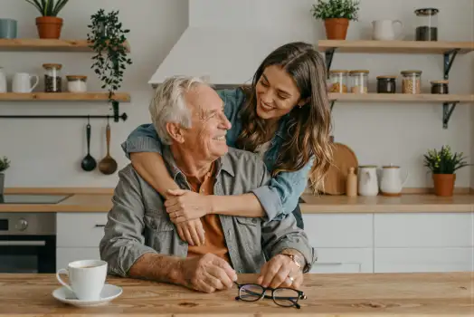 Elderly Man Smiling at Young Woman in Kitchen