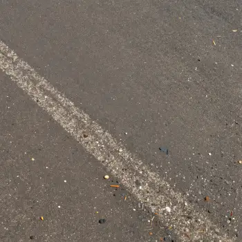 Straight white line on asphalt road with debris
