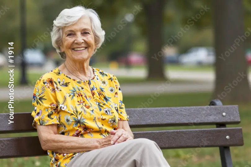 Elderly Woman Smiling on Wooden Bench in Park
