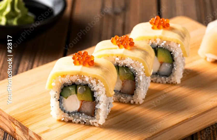 Sushi Rolls with Sesame Seeds on a Cutting Board