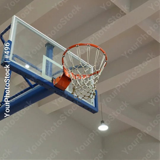 Dunking basketball hoop in gymnasium ceiling blue