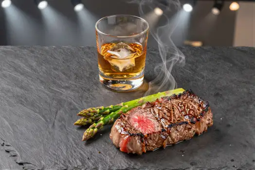 Medium-rare Steak with Herbs and Whiskey in Bar Setting