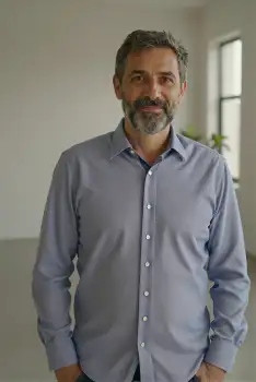 Middle-aged man smiling in empty room light blue shirt