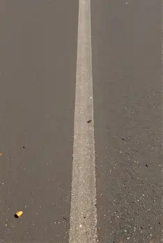 Uneven white line on asphalt with cigarette near parking lot