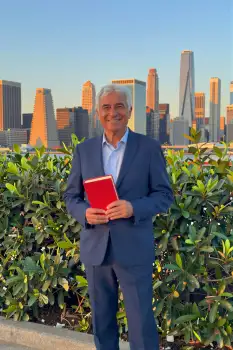 Elderly Man Holding Book in Front of City Skyline