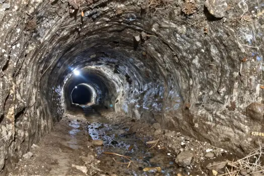 Tunnel Interior Walks Through Rock Wall With Small River