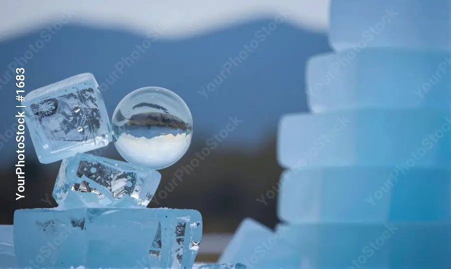 Stacked Ice Cubes Floating in Glass with Mountain Landscape Background