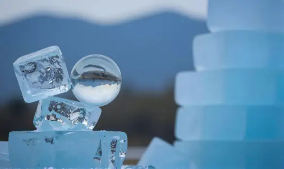 Stacked Ice Cubes Floating in Glass with Mountain Landscape Background