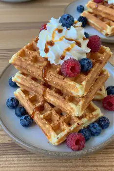 Stack of Golden Brown Waffles with Whipped Cream and Caramel Sauce