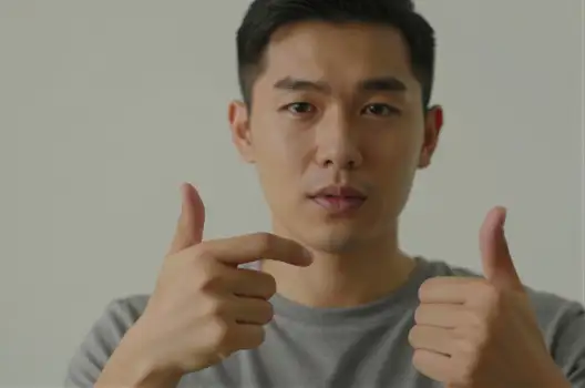 Young man making a thumbs up with serious expression