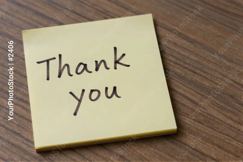 Close-up of 'Thank you' sticky note on wood wooden surface