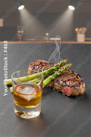 Medium-Rare Steak with Asparagus and Whiskey on Black Countertop