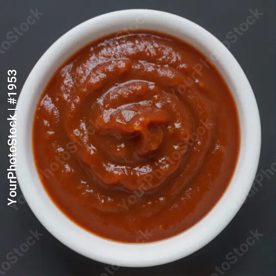 Close-up of a small white bowl filled with thick red sauce ketchup