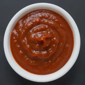 Close-up of a small white bowl filled with thick red sauce ketchup