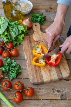 Hands Cutting Bell Pepper on Wooden Board kitchen