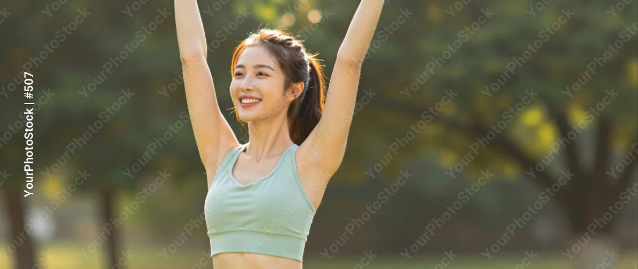 Happy young woman raising arms in park sunny day asian fitness