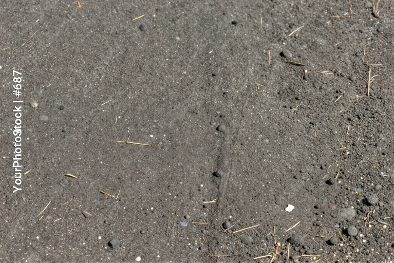 Footprint in Black Asphalt with Debris rock pebble