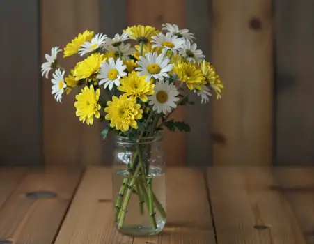 Yellow and White Daisies in a Glass Vase on Wooden Table