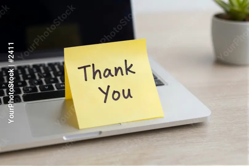 Laptop with Thank You note on wooden desk sticky note