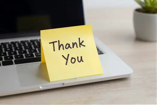 Laptop with Thank You note on wooden desk sticky note