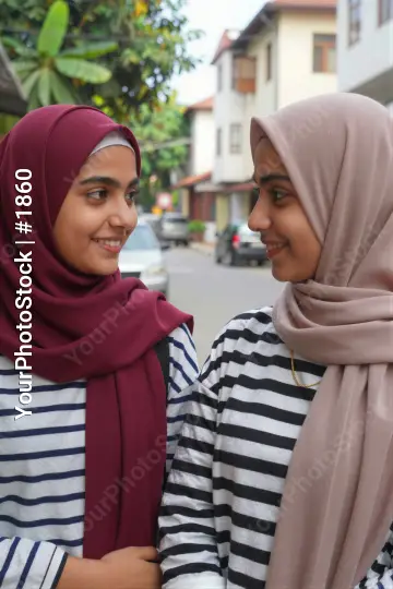 Two young women smiling and conversing on a street