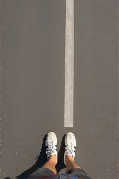 Person jumping on concrete floor, sneakers, blue shorts