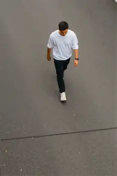 Man Walking on Concrete Pavement casual wear serious expression