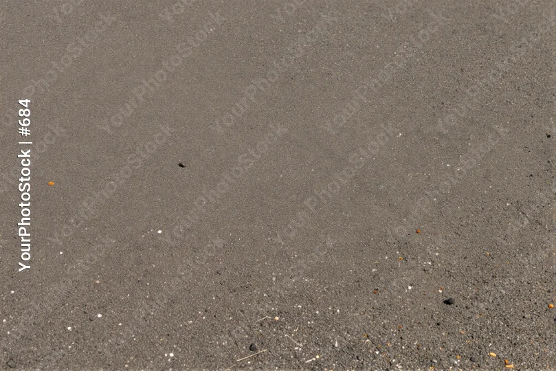 Grayish-brown textured asphalt or concrete surface with scattered