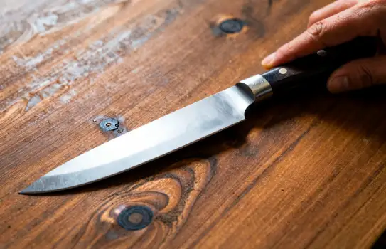 Close-up of a shiny knife blade on rustic wooden surface