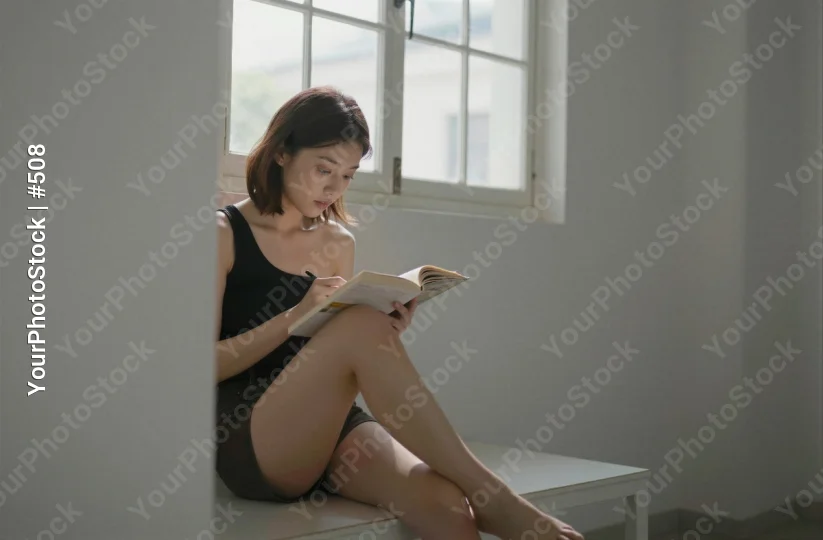 Young Woman Reading Peacefully by Window book asian