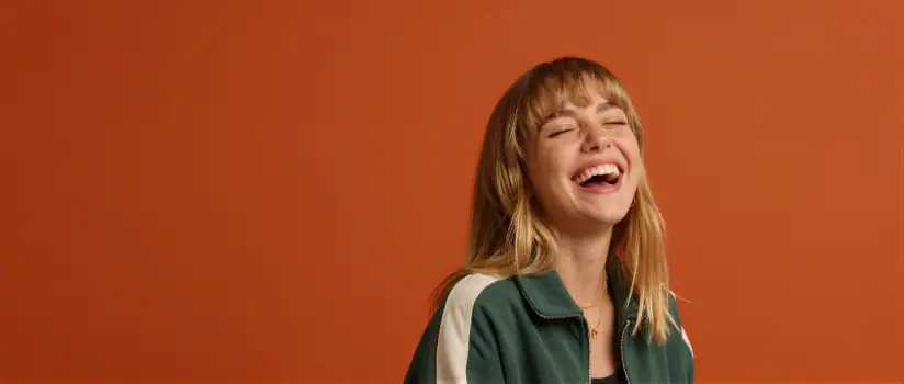 Young Woman Laughing with Closed Eyes in Green Jacket