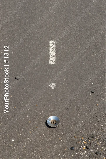Close-up of gray asphalt with screw or nut on ground