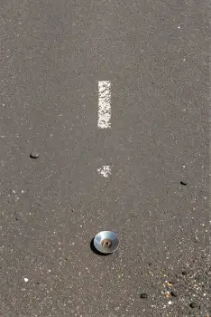 Close-up of gray asphalt with screw or nut on ground