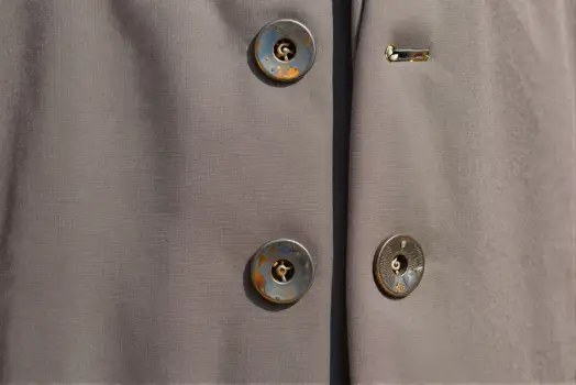 Close-up of Beige Trousers with Silver Metal Buttons and Gold Hook