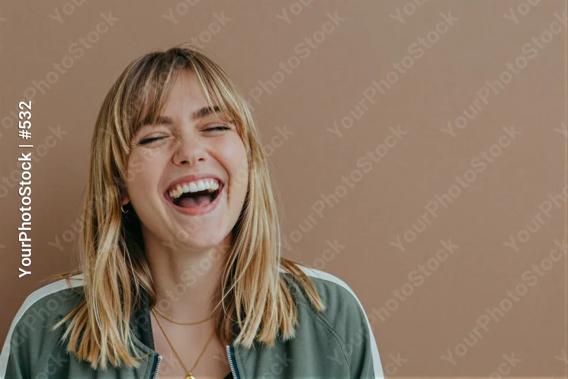 Young woman with blonde hair laughing in green jacket