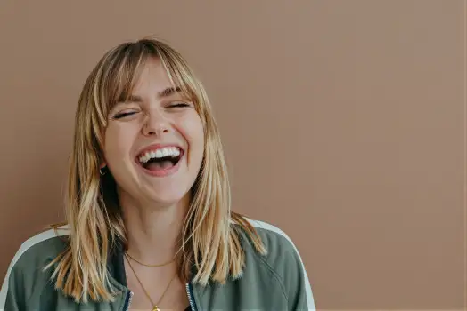 Young woman with blonde hair laughing in green jacket