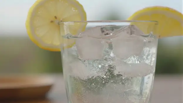 Refreshing Lemon Water with Ice on Wood Table