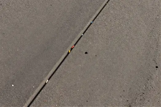 Uneven concrete line with marks asphalt hole dirt