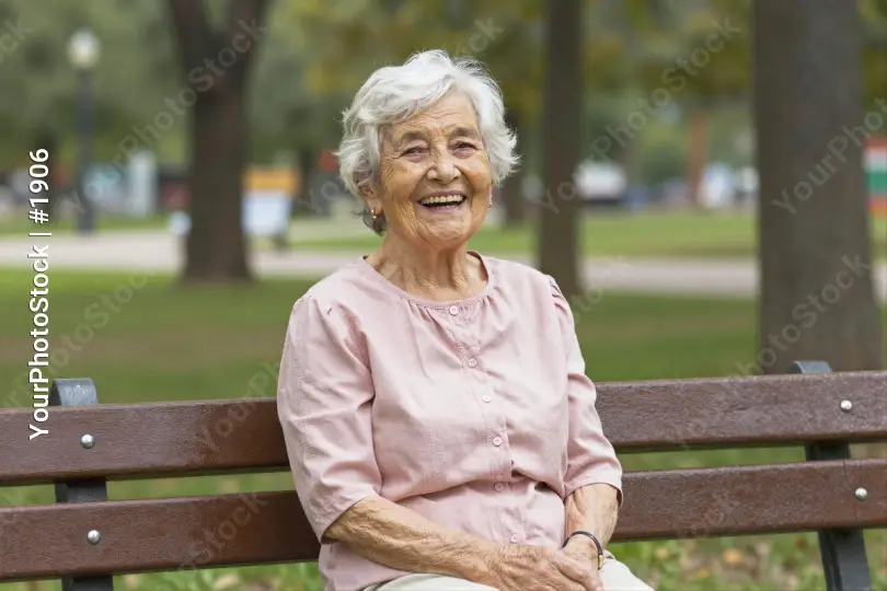Elderly Woman Smiling on Wooden Bench in Park