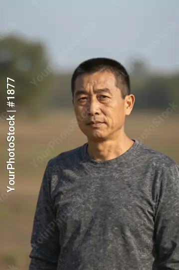 Middle-aged Asian man standing in a field serious