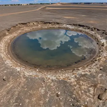 Circular Mud Puddle Reflecting Sky in Open Field