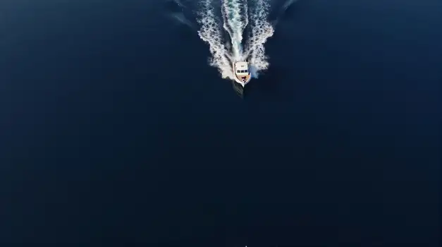 Fast-moving white boat with wake in deep blue ocean