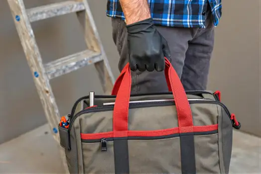 Person Holding Duffel Bag plaid shirt gloves grey bag worker