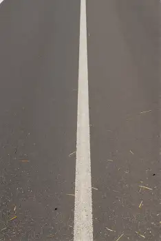 Smooth white line on uneven gray asphalt uneven surface